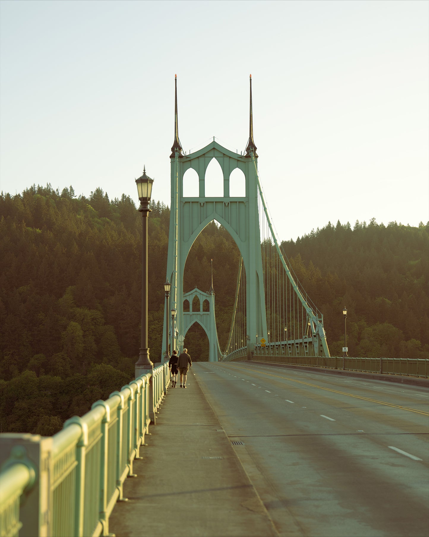 two people walking on the st johns bridge on a hot summer day in portland oregon