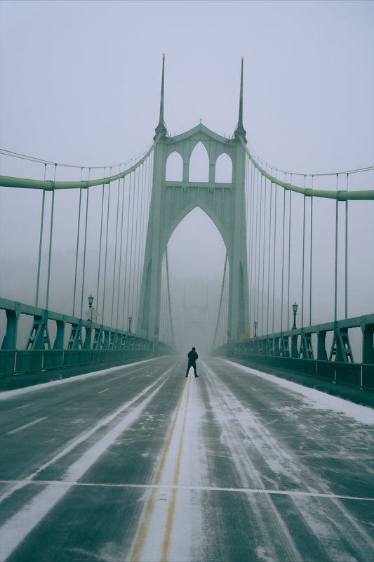 a man standing in the middle of the st johns bridge during a snowstorm